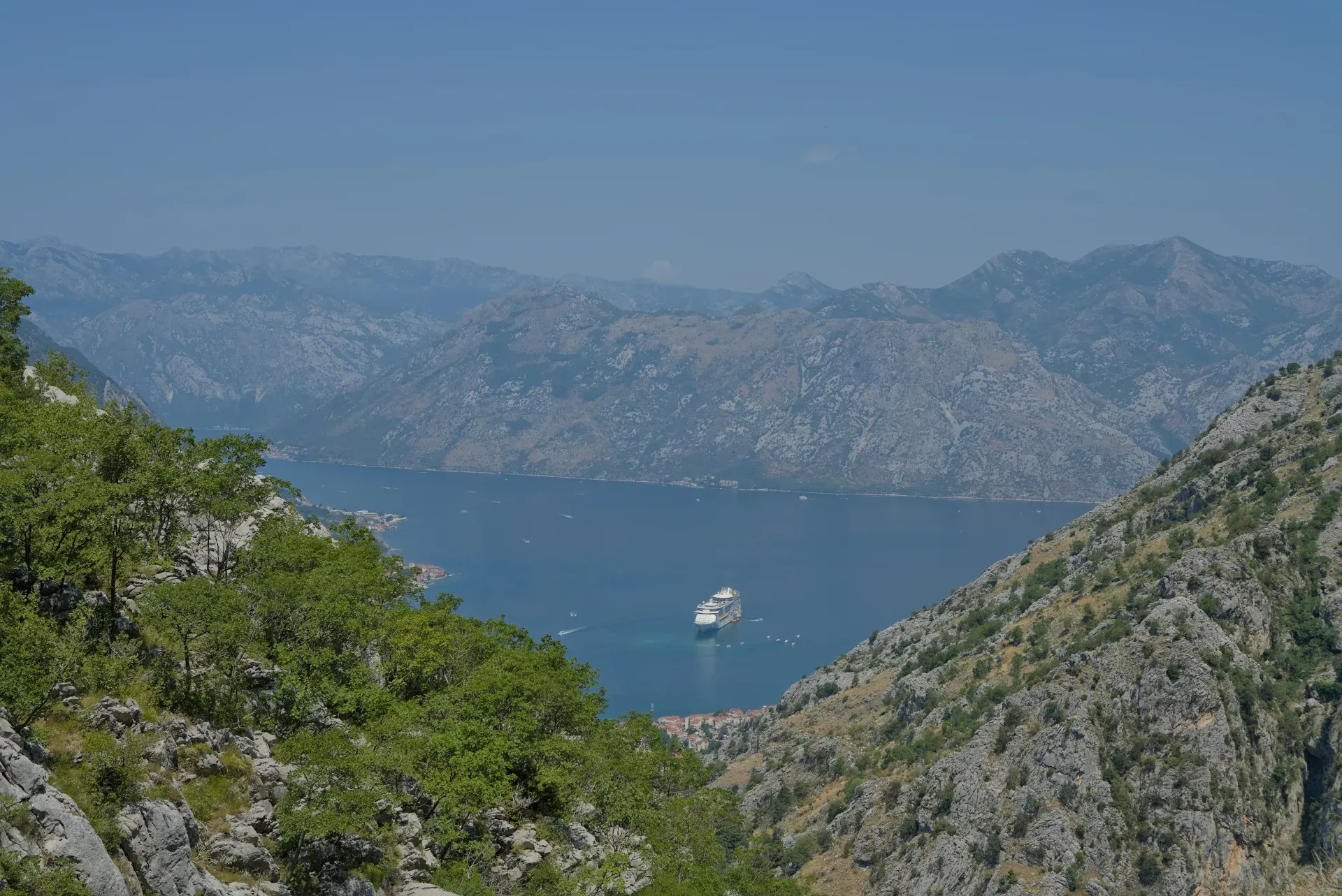 Vista della Baia di Kotor in Montenegro da una montagna attraverso rocce, con una nave da crociera nell'acqua.