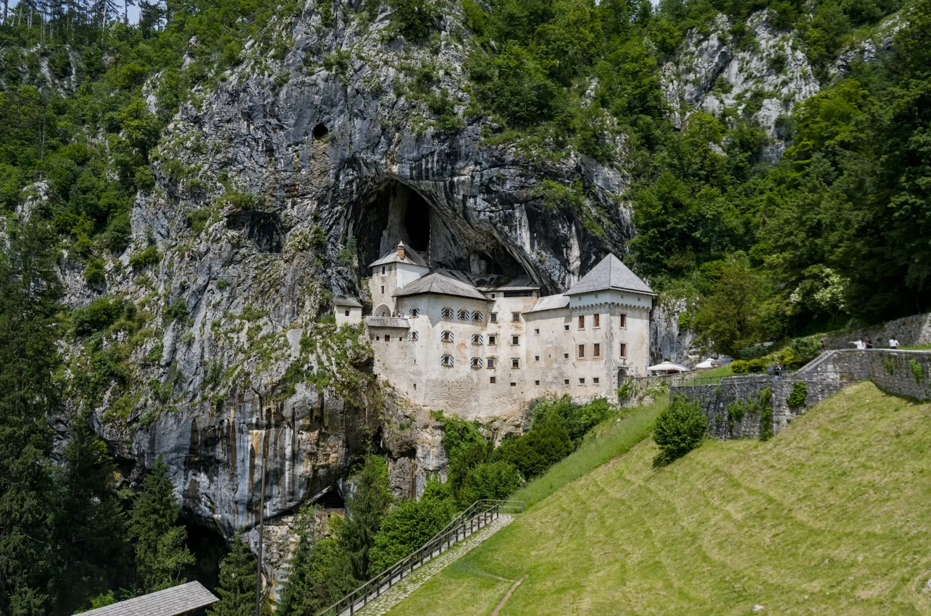 Istorijski Predjamski zamak se veličanstveno uzdiže iz vertikalne stene u Sloveniji, okružen bujnim zelenilom.
