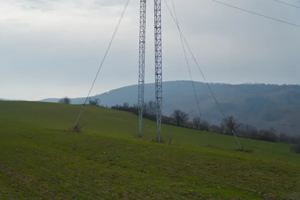 Ein hoher Strommast ragt über die sanften, grünen Hügel von Fruska in Serbien unter einem bewölkten Himmel.