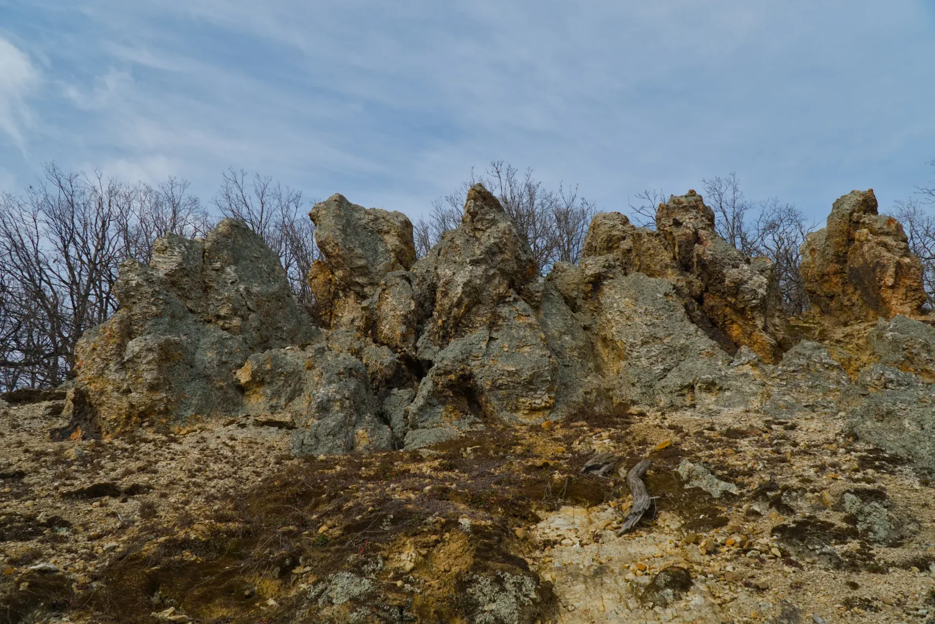 Orlovo Stijene (Roches de l'Aigle) à Fruška Gora, Serbie, avec des formations rocheuses dramatiques et des arbres dénudés en arrière-plan.