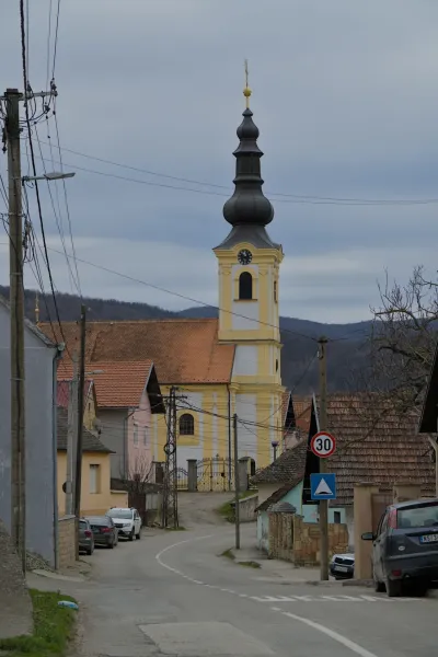 La Chiesa della Trasfigurazione a Beočin, Serbia, con il suo distintivo campanile giallo e bianco, sotto un cielo coperto.