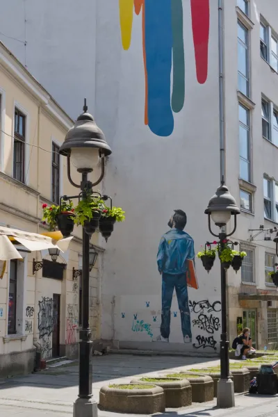 Rue Knez Mihailo à Belgrade avec une fresque murale et des lampadaires vifs.