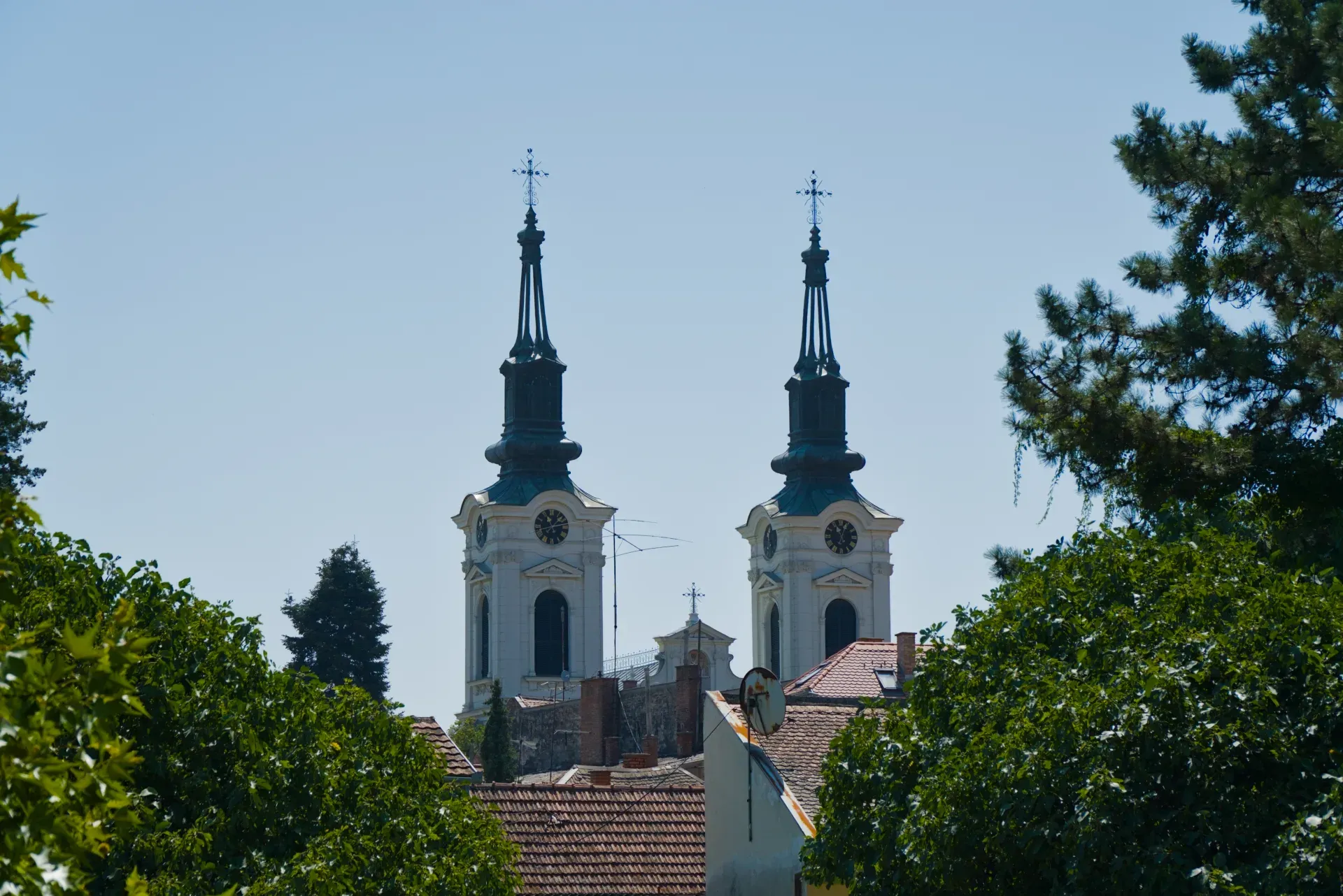 Zwei Glockentürme der Nikolaikirche in Sremski Karlovci, Serbien, vor einem klaren blauen Himmel.