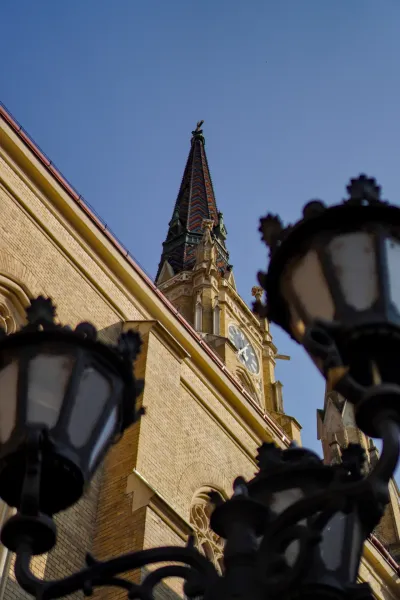 Foto des Mariä-Tempels in Novi Sad, Serbien, mit Ziegeldach und Uhr, aus niedrigem Blickwinkel aufgenommen.