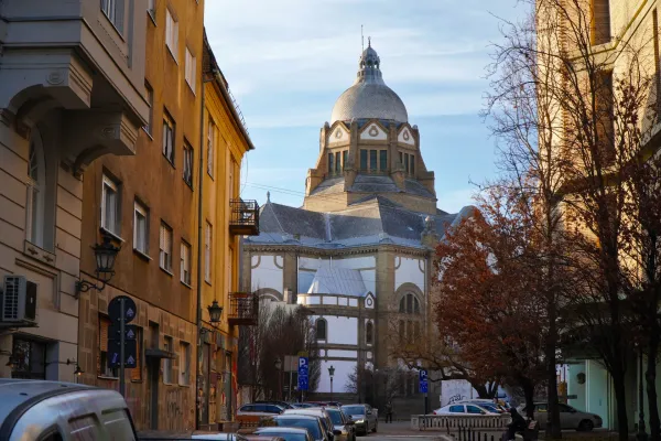 View of the Synagogue from Petra Drašin Street in Novi Sad, Serbia, with golden buildings and blue sky.