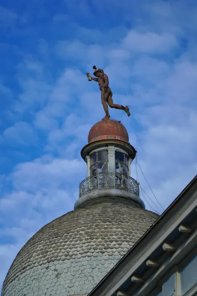 Estatua de Mercurio, dios del comercio, en la cúpula del Banco de Serbia en Novi Sad sobre un cielo azul.