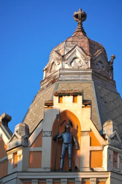 Statua di cavaliere sul tetto dell'Hotel Queen Palace a Novi Sad, Serbia, con cielo blu sullo sfondo.