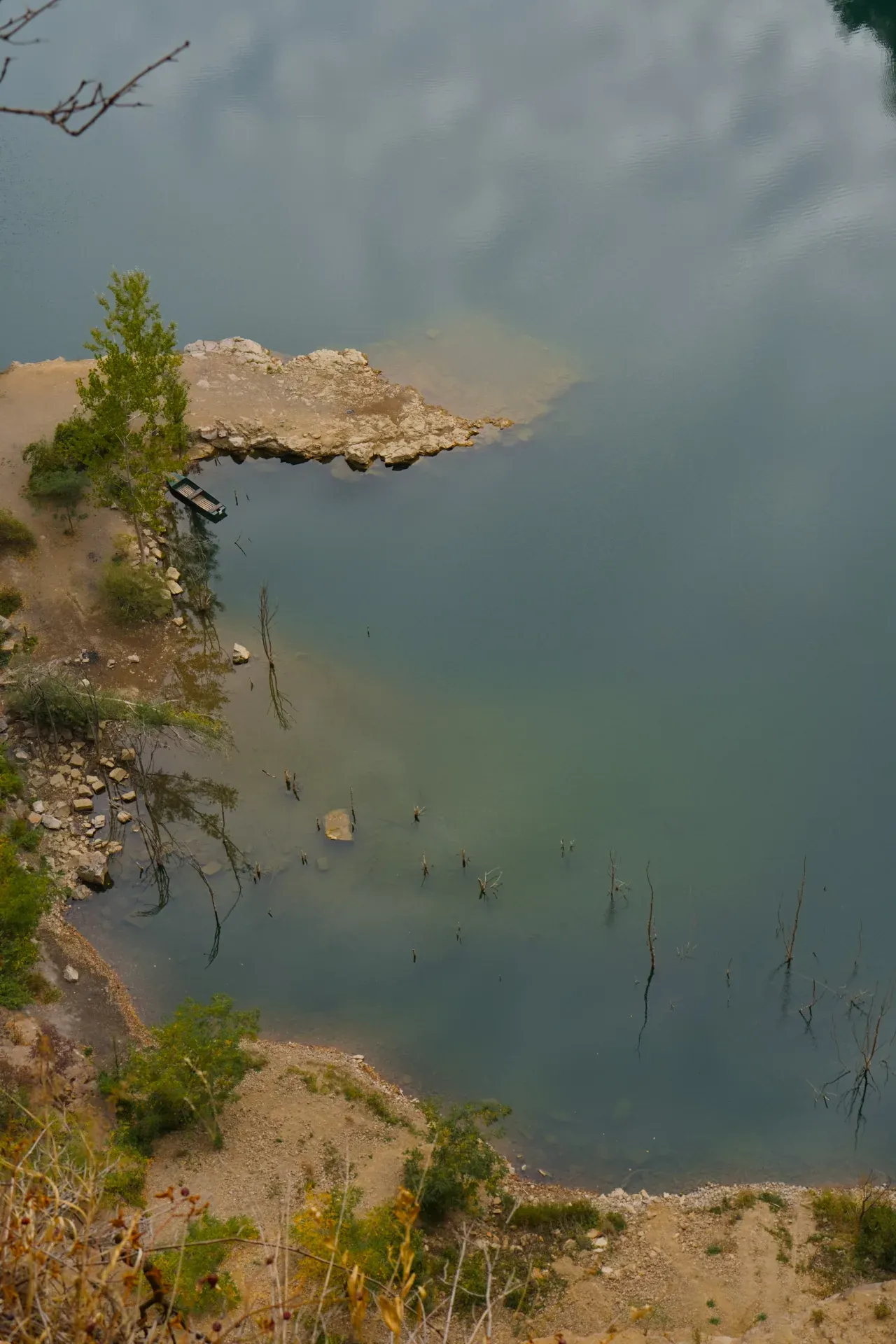 Una barca sul lago Ledinačko di prima mattina, che riflette le nuvole nell'acqua calma.