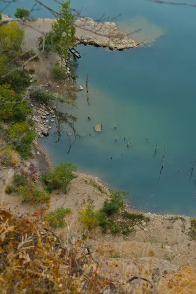 Лодка пришвартована у берега Лединачкого озера с прозрачной водой, снято с высоты.