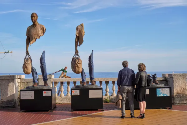Eine Ansammlung von Steintürmen und Wohngebäuden befindet sich auf einem dicht bewaldeten Hügel in Genua, Italien, unter einem strahlend blauen Himmel.