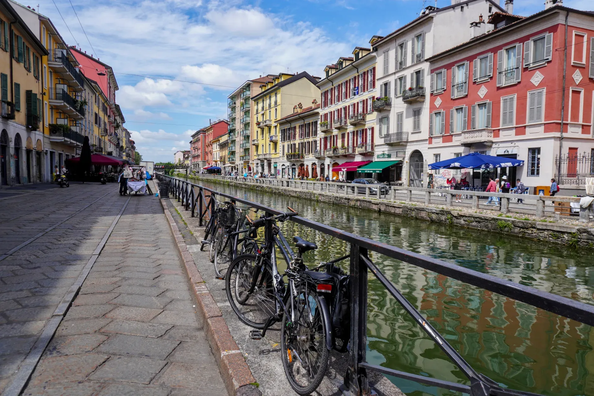 Ein Kanal im Mailänder Navigli-Viertel mit Drachenbooten, die Rennen fahren, flankiert von bunten Gebäuden und Außenbereichen.
