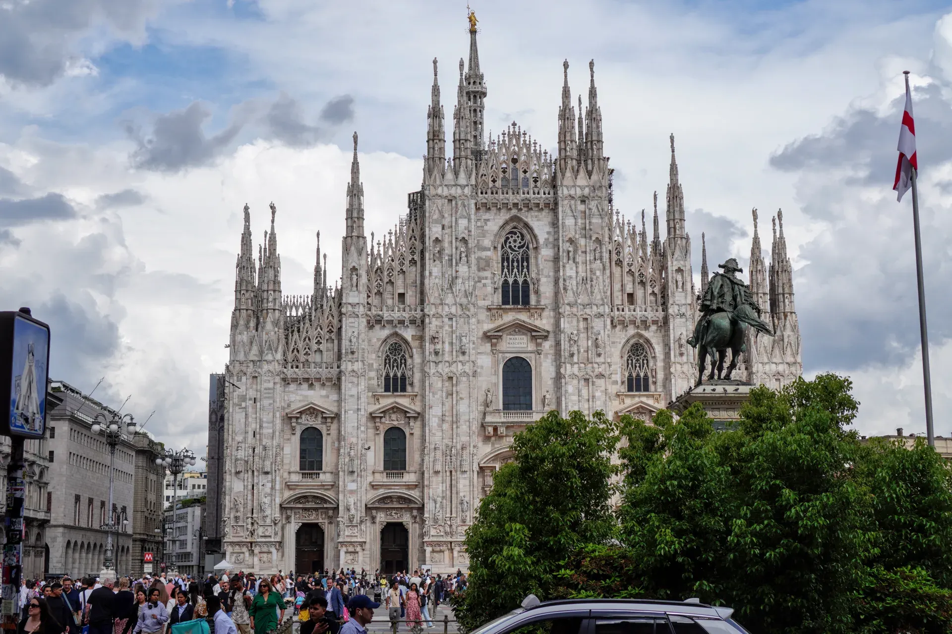 Una vista generale di Piazza Duomo a Milano, Italia, con l'iconico Duomo di Milano sullo sfondo e molte persone che passeggiano nella piazza.