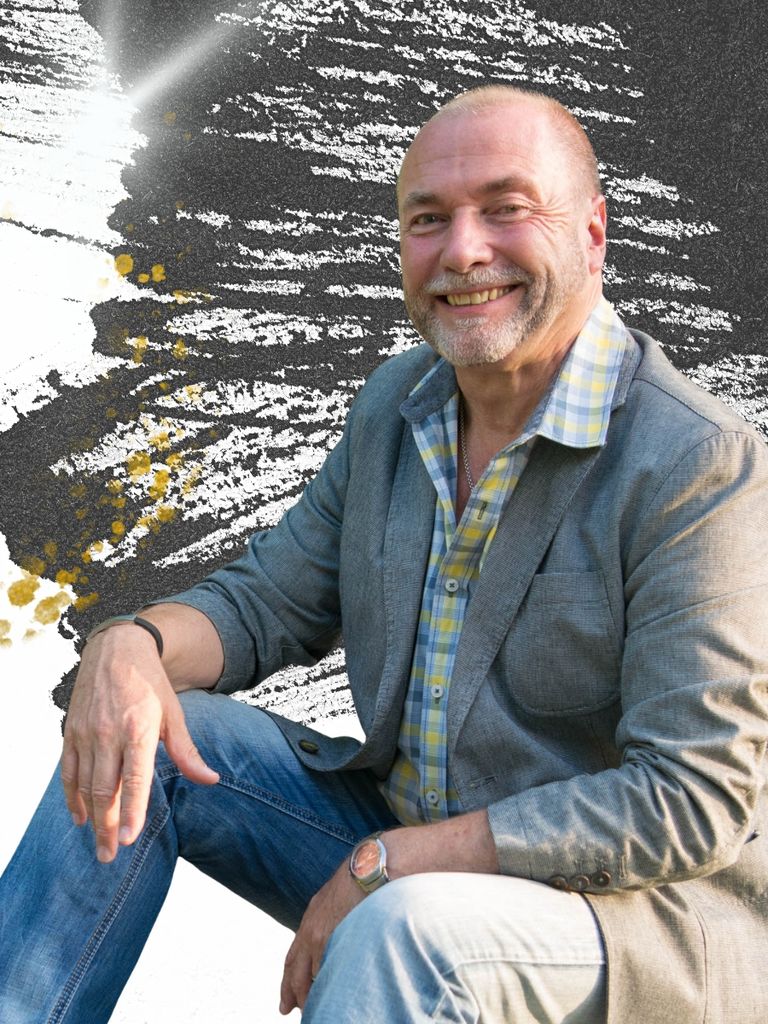 Mann sitzt und lacht vor schwarzem Hintergrund