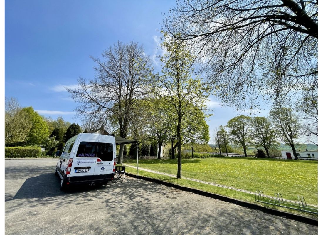 Stellplatz auf einem Hallenvorplatz neben einer grünen Wiese — Місце для кемперів in Borgentreich