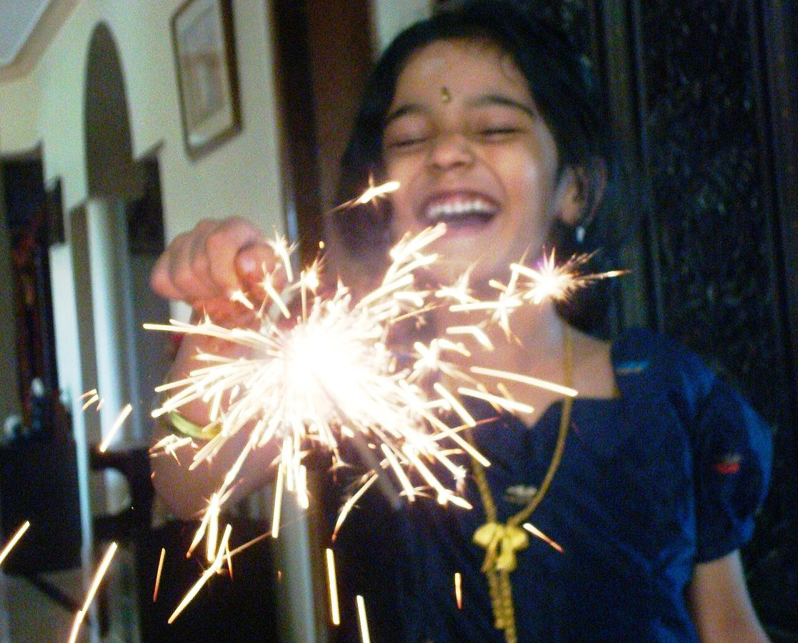 Dziecko bawiące się fuljhadi, iskrzącymi zimnymi ogniami podczas Diwali