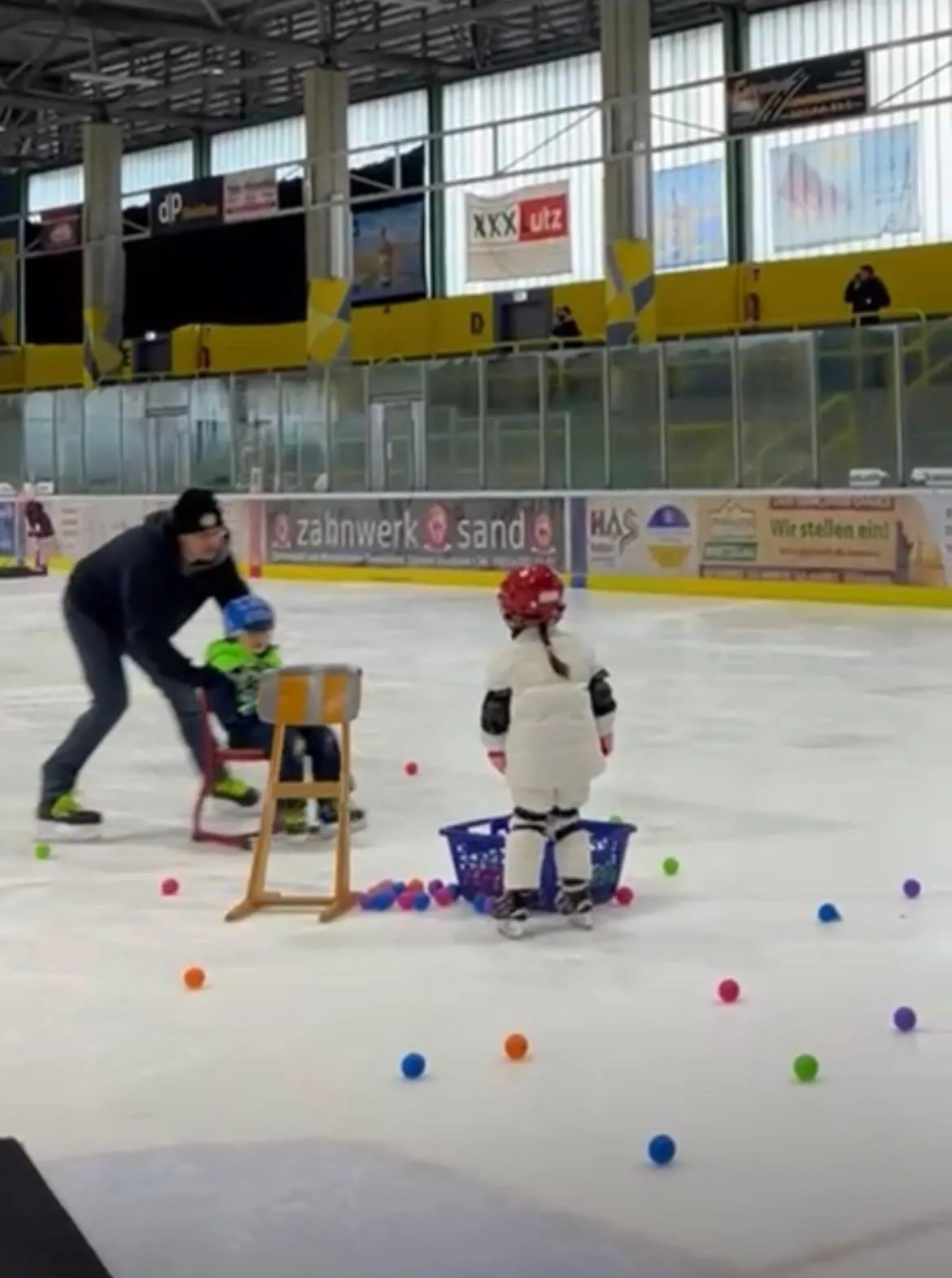 Laufschul-Kinder üben mit bunten Bällen auf dem Eis