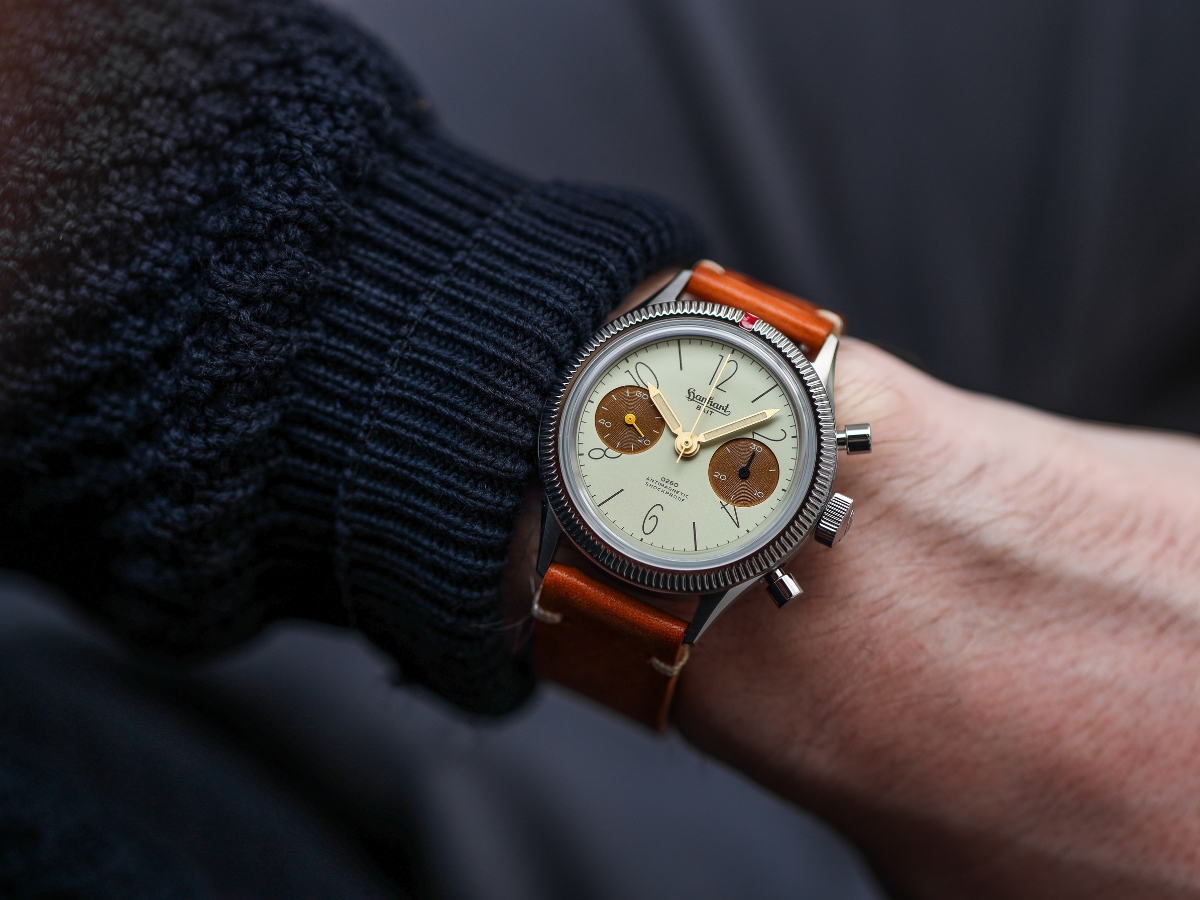 Chronograph mit cremefarbenem Zifferblatt, braunen Totalisatoren und braunem Lederband am Handgelenk, darüber dunkler Strickpullover