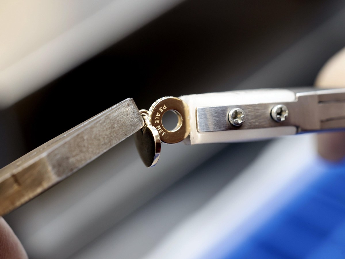 Nahaufnahme: Herzanhänger mit geprägtem Ring wird in der Fertigung mit einer Zange gehalten