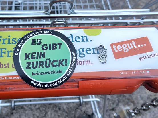 Runder Aufkleber mit dem Inhalt: Schwarzer Außenrand "Die Welt verändert sich. Mach mit und bleib nicht hängen". In der Mitte auf grünen Hintergrund: "Es gibe kein zurück. keinzurück.de"
