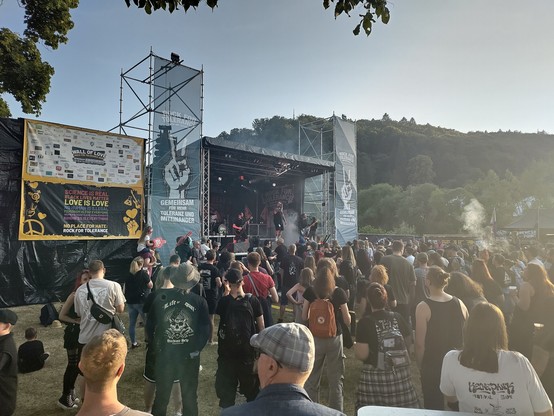 Bühne im Tageslicht. Publikum im Vordergrund, Berge im Hintergrund