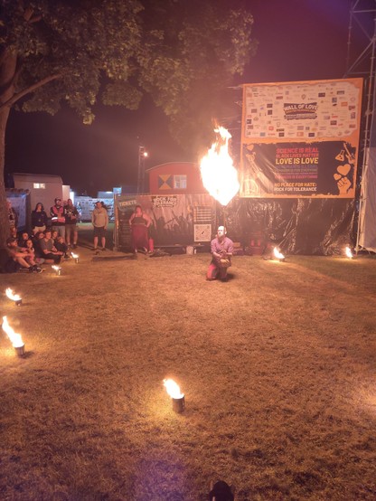 Feuerkünstler der ein brennendes Herz hochhält in einem durch kleine Feuerschalen abgesteckten Kreis
