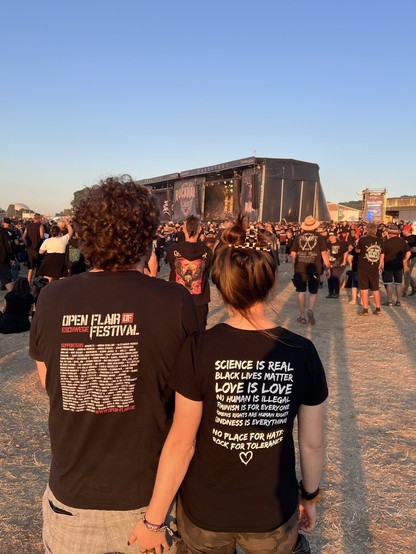 Zwei Personen von hinten vor der Bühne des Rock Harz im Sonnenuntergang. Linke Person trägt T-Shirt mit der Aufschrift "Open Flair Festival Eschwege Supporters"
Rechte Person trägt T-Shirt mit

"Science is real
Black lives matter
Love is love
No human is illegal
Feminism is for everyone
Womens rights are human rights
Kindness is everything

No place for hate:
Rock for Tolerance"