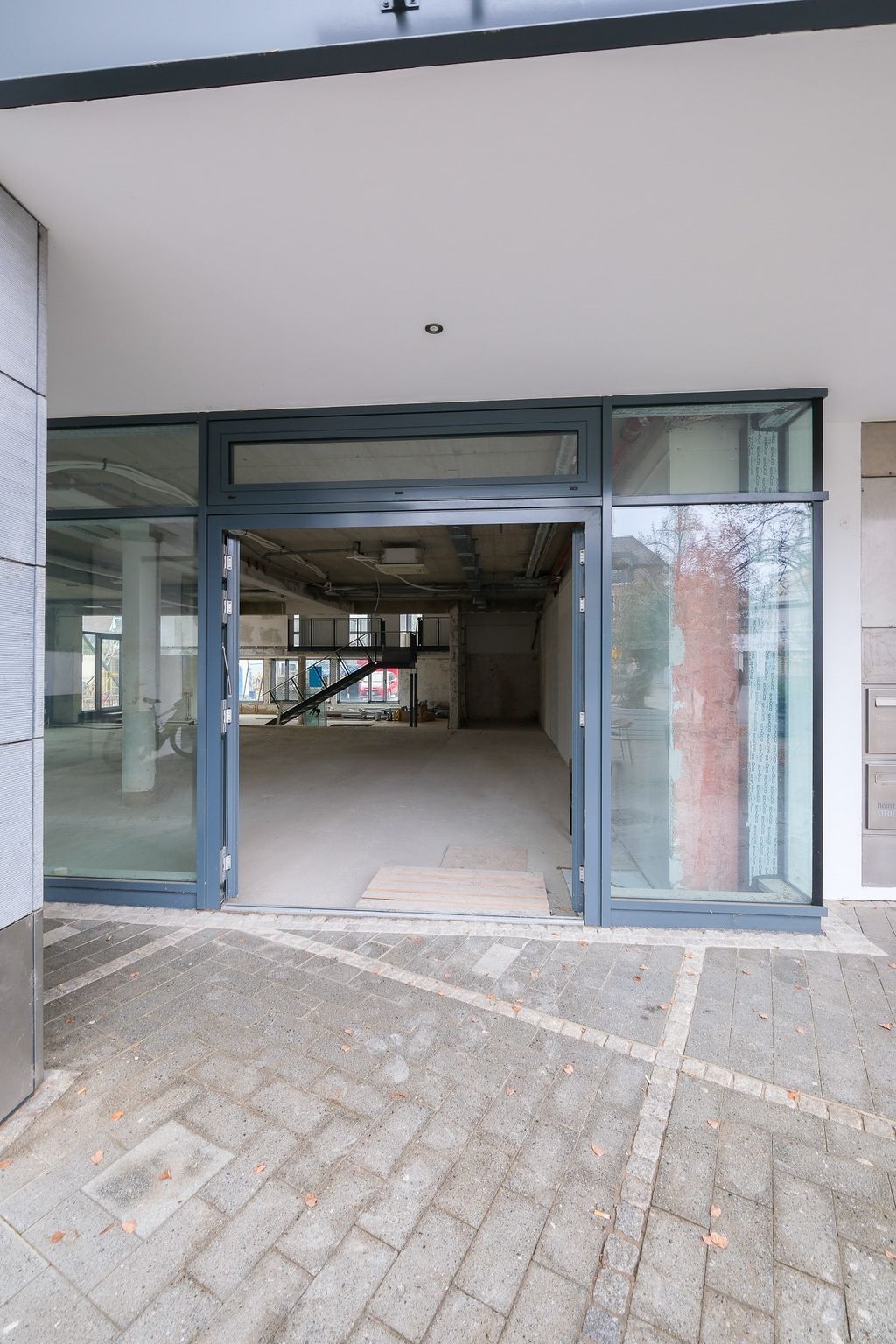 Empty retail space with a wide glass frame and open entrance in a modern building.