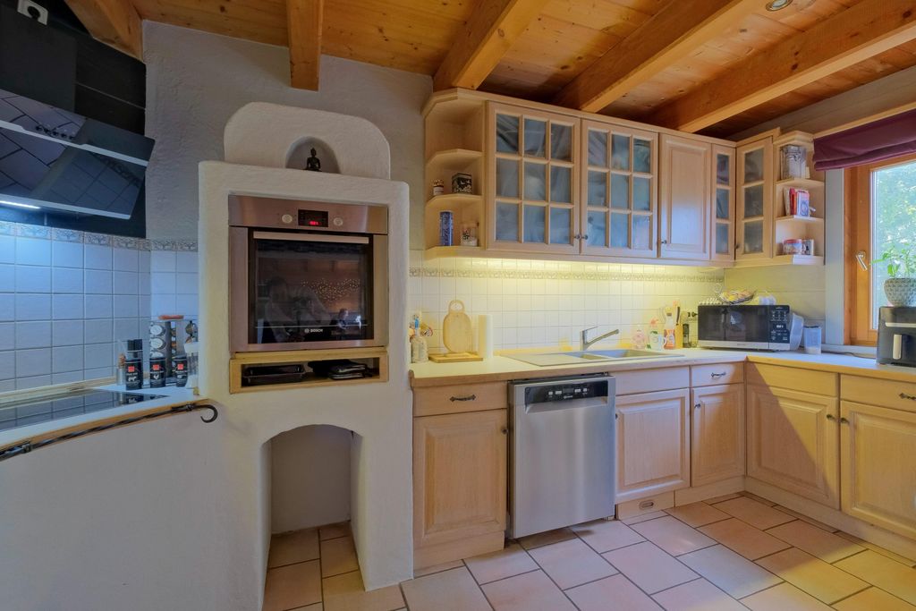 Bright kitchen with rustic wooden ceiling, built-in oven, dishwasher, microwave, and a window with purple blinds.