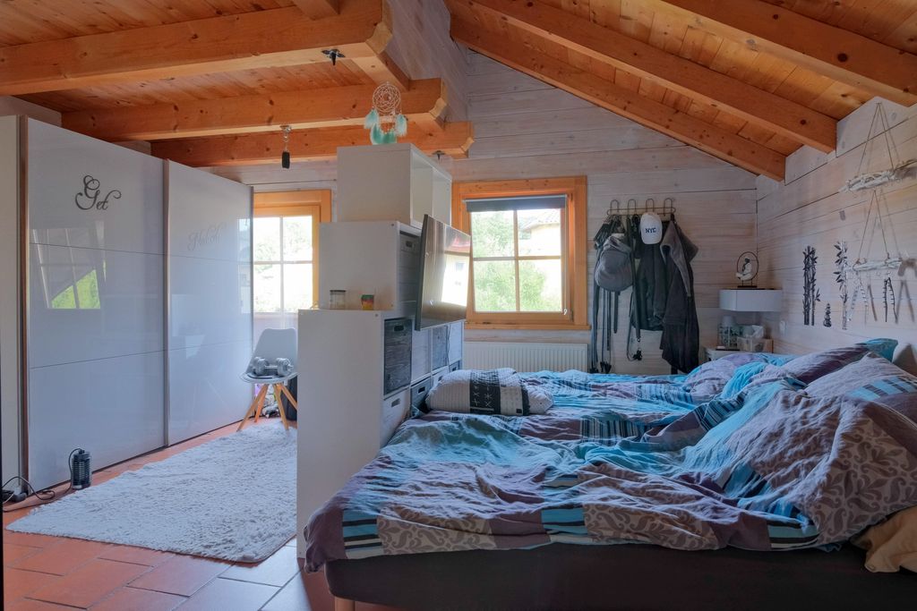 A cozy bedroom with a wooden beam ceiling, two beds with patterned bedding, and white sliding doors with mirrors on one wall.