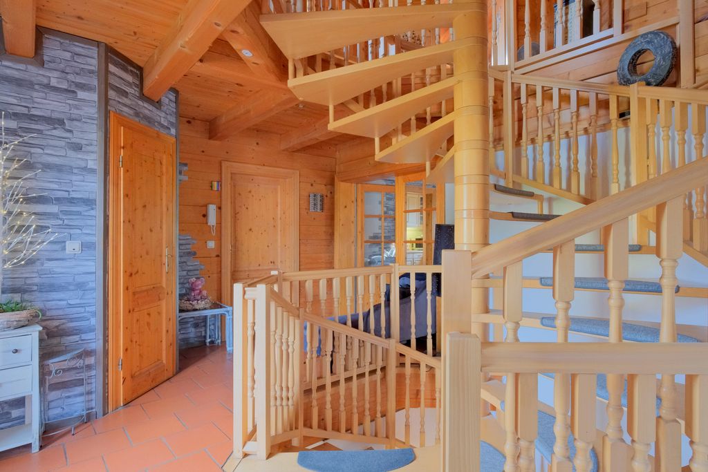 Bright, cozy interior featuring a light wooden spiral staircase and a door with stone-clad wall.