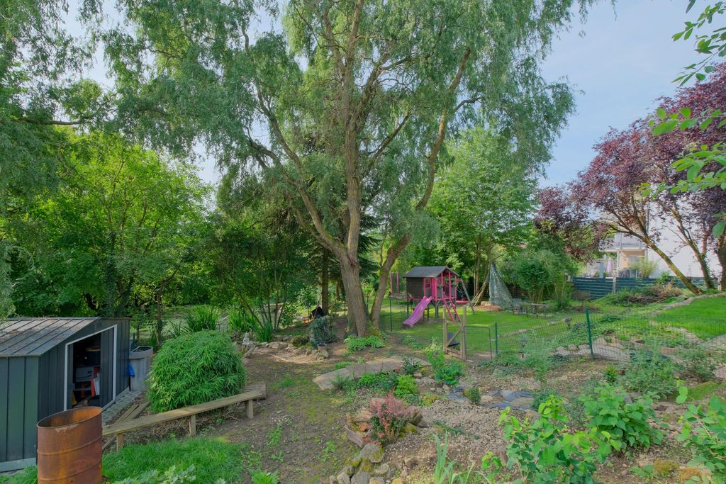 Garden with many trees, a small playhouse with slide, a tool shed, and a path running through the green area.