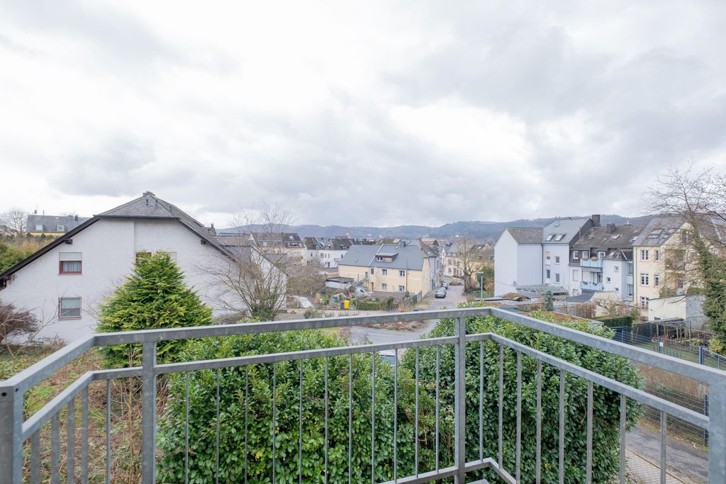 View from a balcony over a residential street with multi-story houses under a cloudy sky.