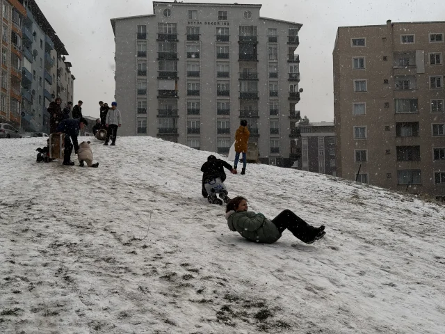 Erzurum'da kar yağışını fırsat bilen çocuklar mahalle aralarında poşetlerle kaydı