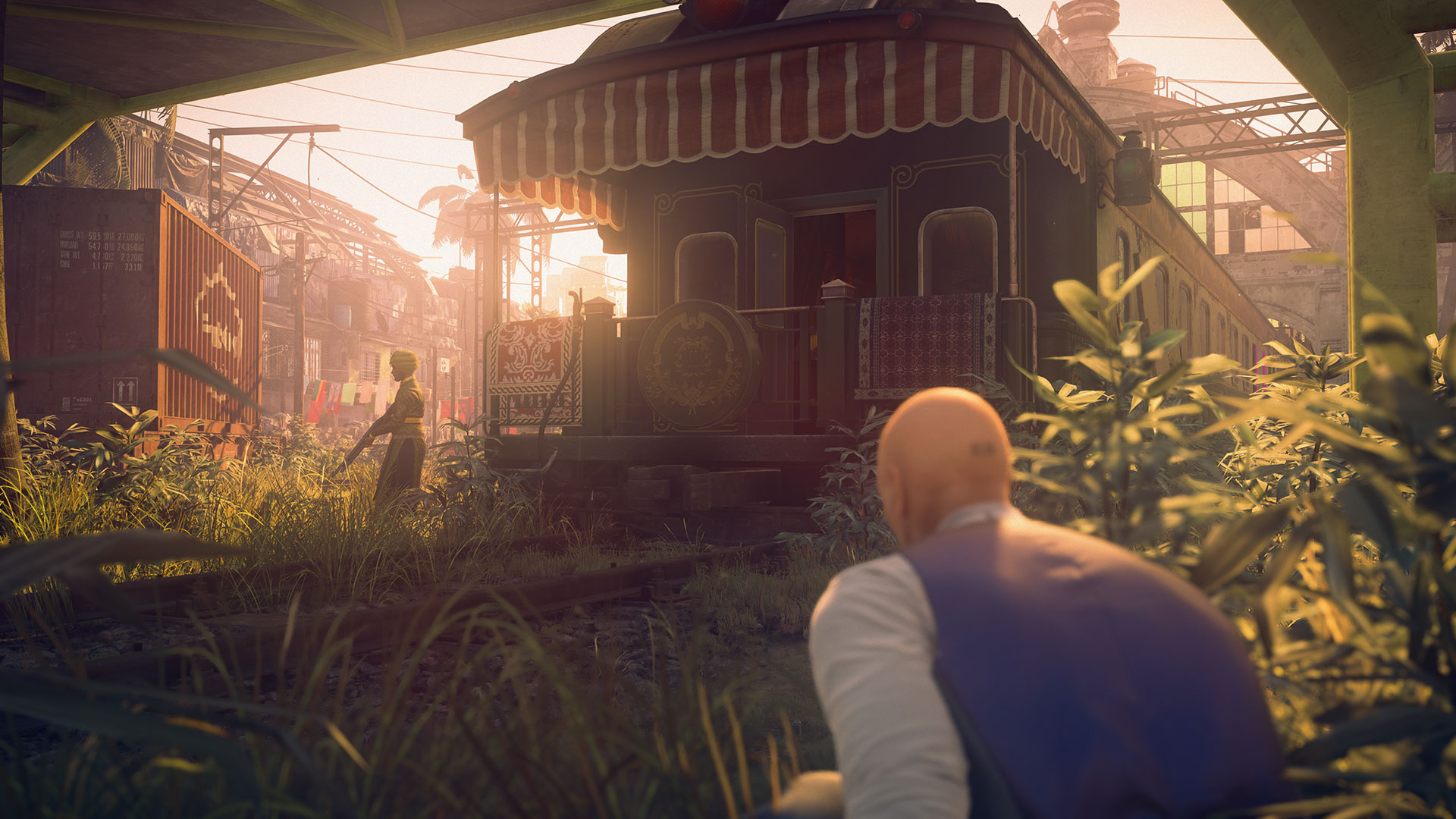 Agent 47 crouches in a trainyard in Hitman 2