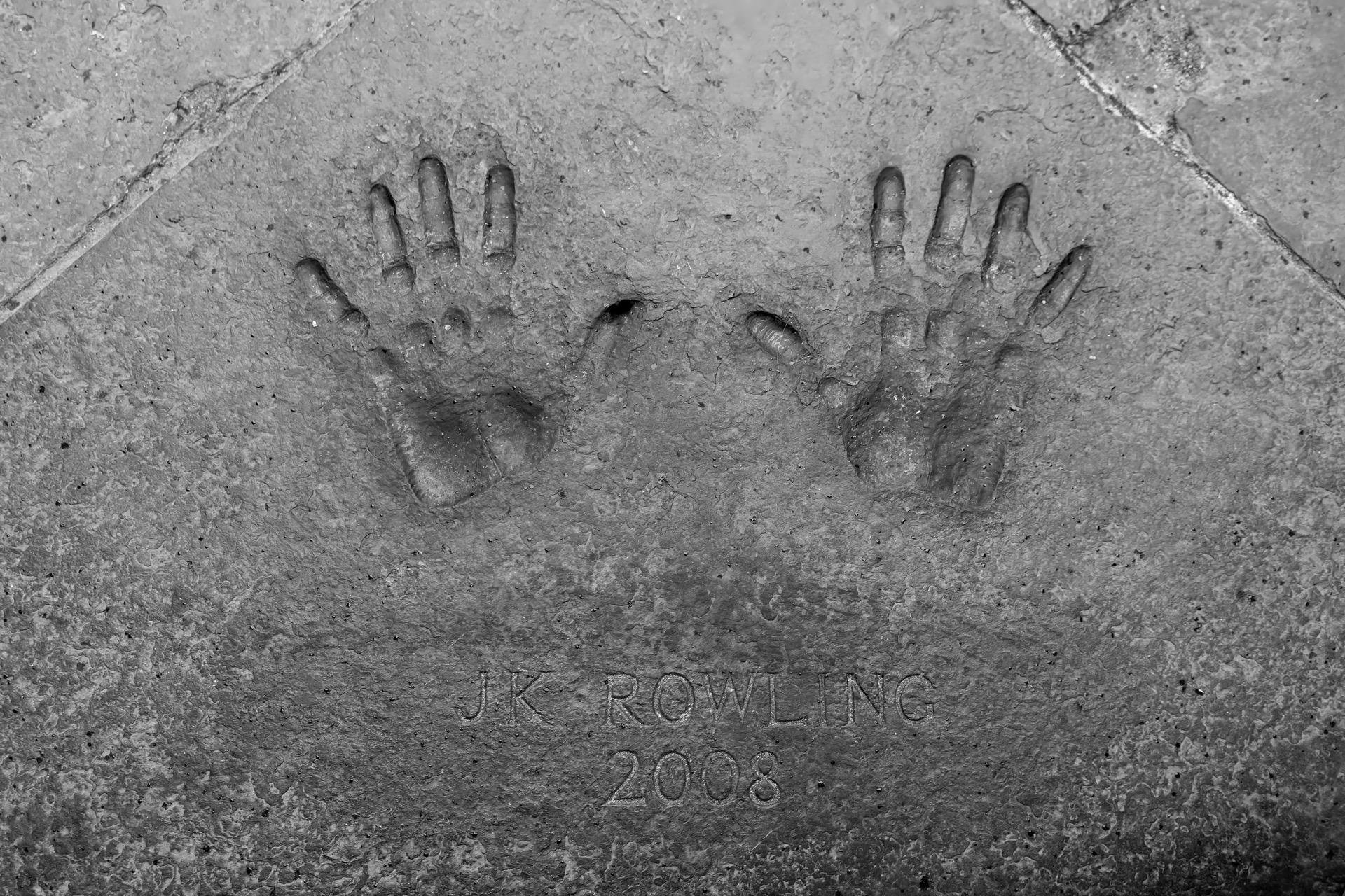 Handprints set in concrete with the engraved name "J.K. Rowling 2008" beneath them. The surface is textured and appears weathered.